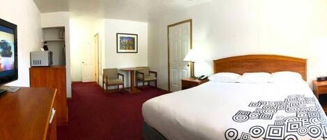 Una habitación de hotel con cama, escritorio, televisor y puerta.