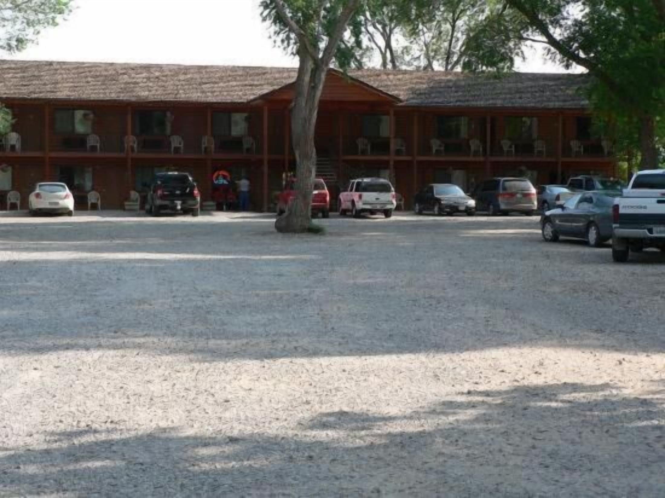 Een gebouw met meerdere kamers en een parkeerplaats met grind.