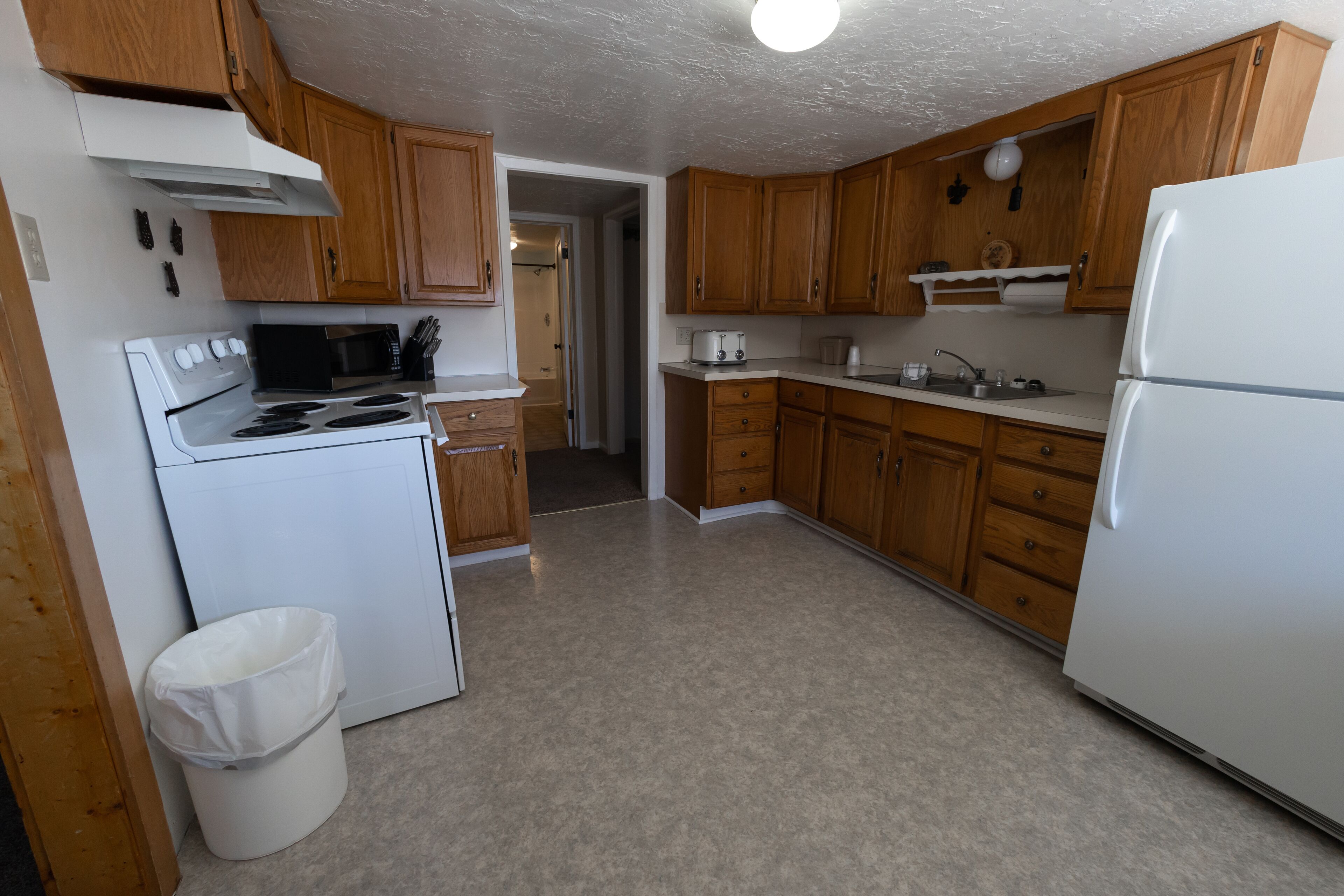 Une cuisine avec des meubles de rangement en bois, une cuisinière blanche, un four à micro-ondes et un réfrigérateur.