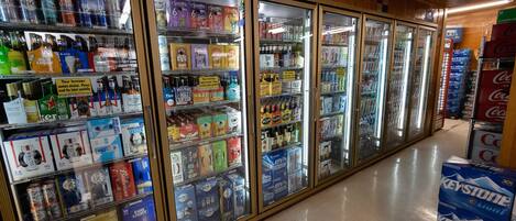 A refrigerated display case in a store with various beverages including beer and soft drinks.