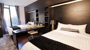 A modern hotel room with a large bed, a desk, and a seating area.