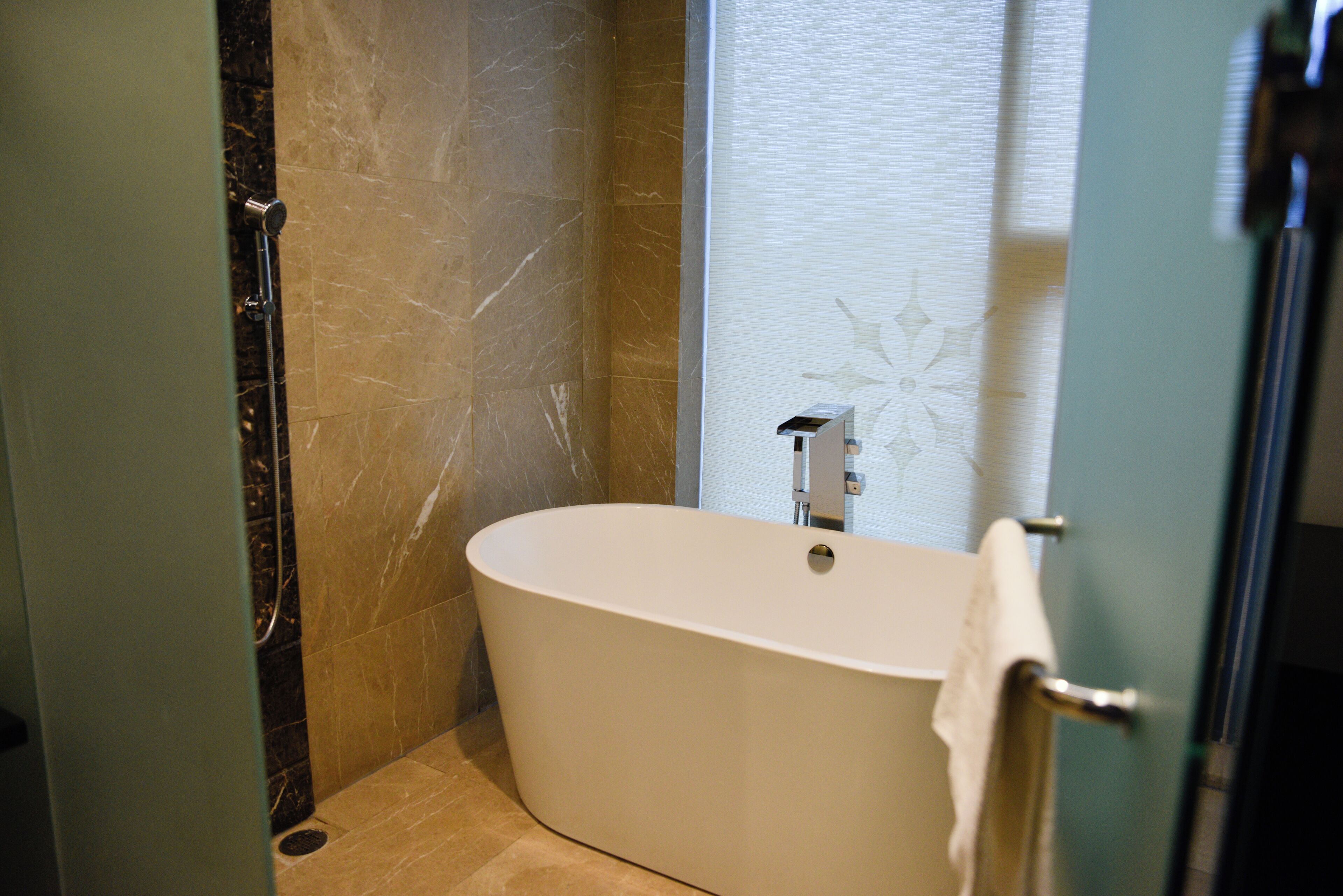 Un baño moderno con una bañera independiente, paredes de mármol y cabina de ducha de vidrio.