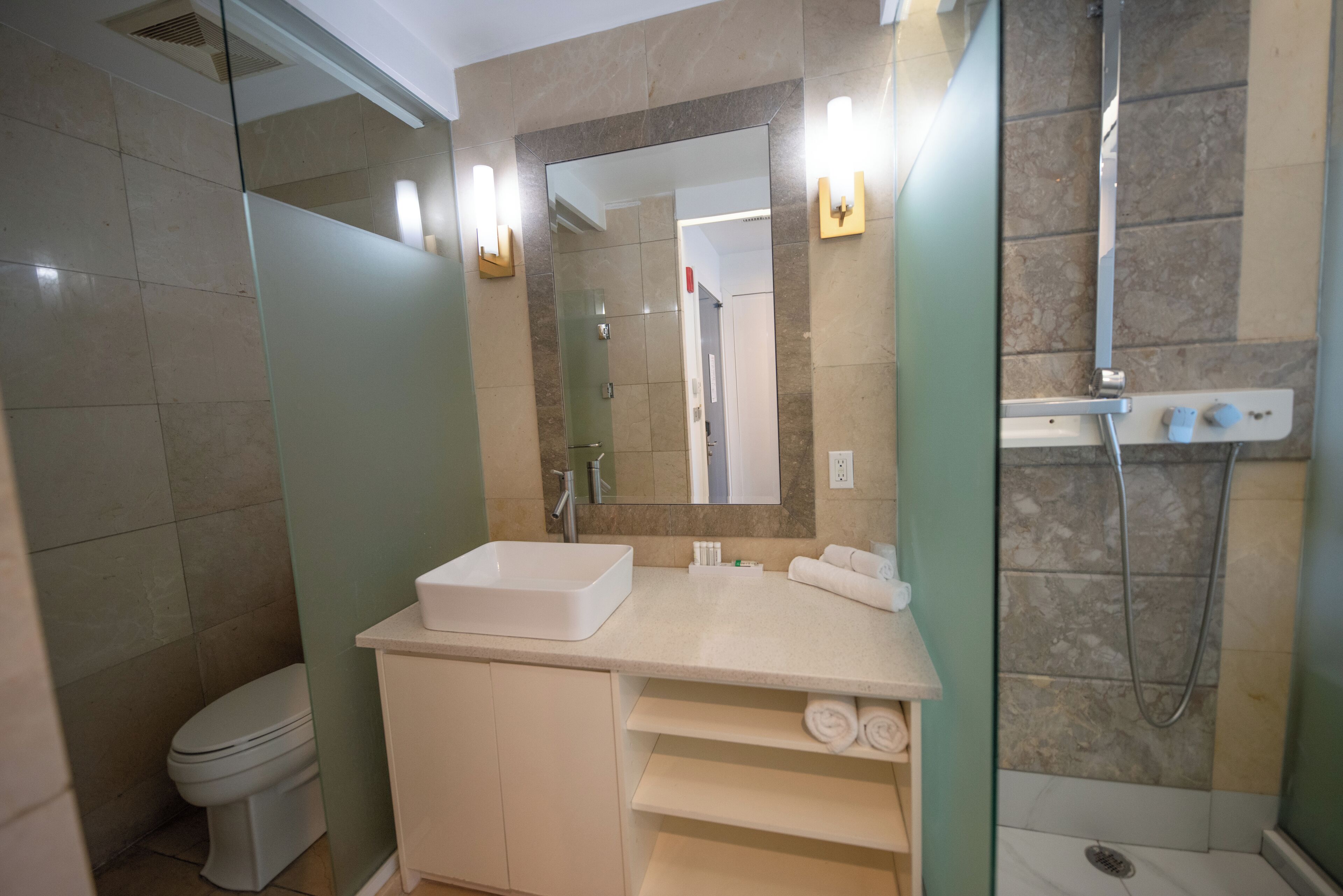 A modern bathroom with a large mirror, a white sink, and a shower area.
