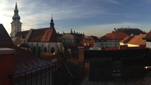 A view of a town with traditional architecture, including a church with a prominent steeple and a hilltop castle. - Hans-Sachs-Gasse 10 (Graz)