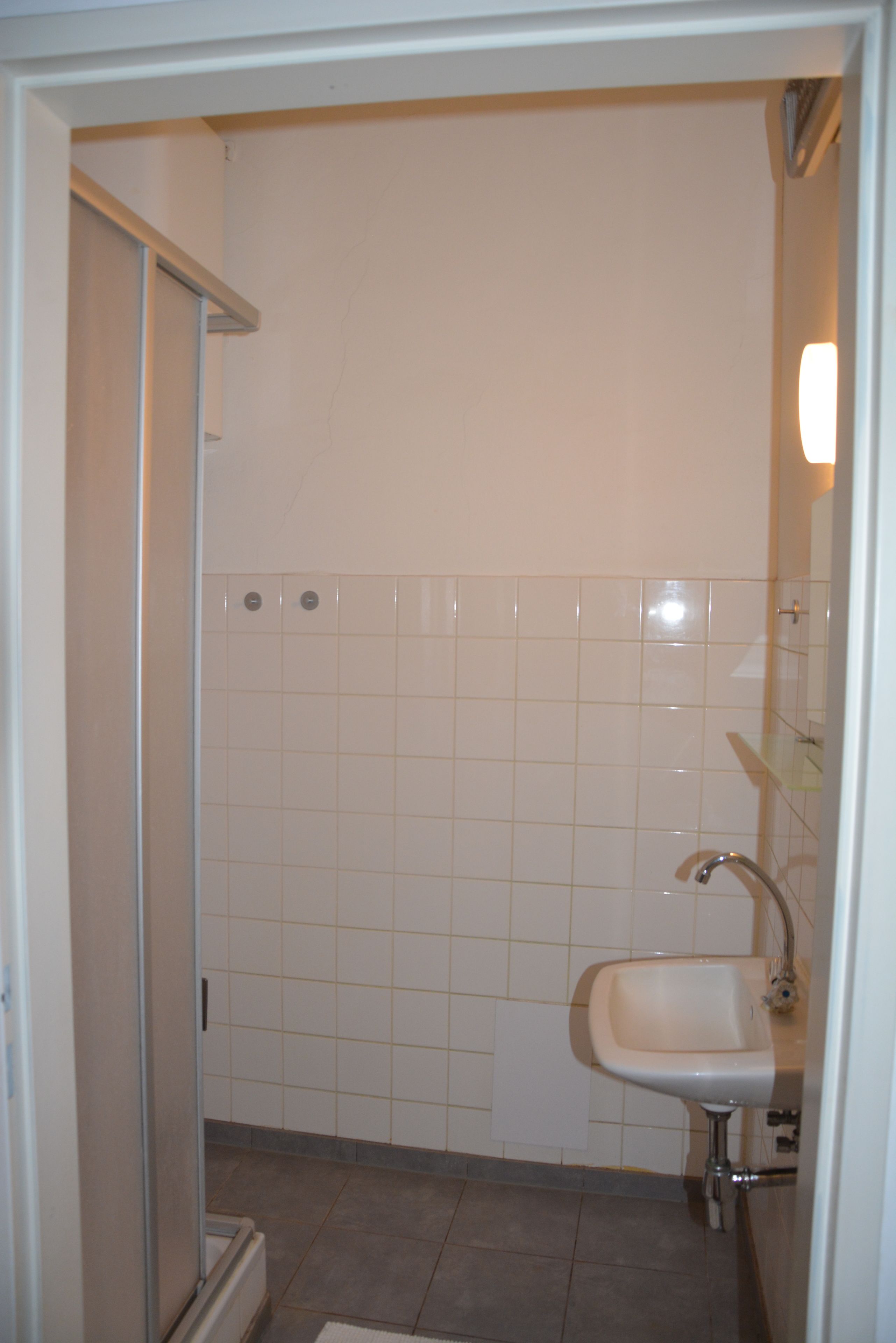 A bathroom with a shower, a sink, and tiled walls.