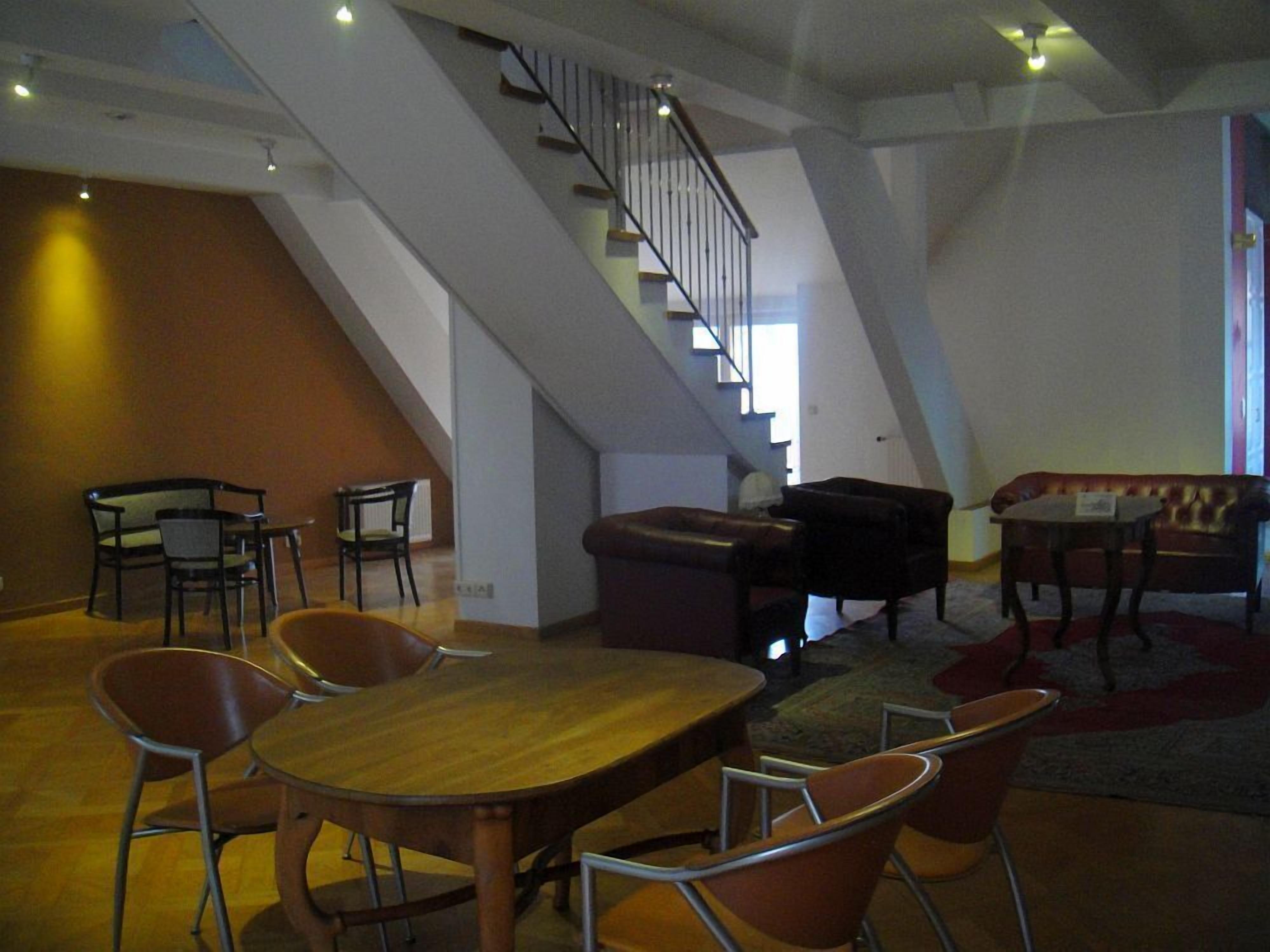 Amplia sala de estar con una mesa de comedor de madera, varias sillas, un sofá y una escalera que sube a un nivel superior.