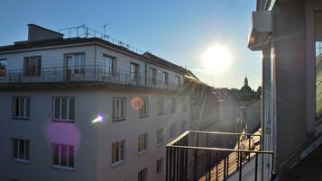 A building with multiple windows and balconies, a clear sky, and the sun shining.