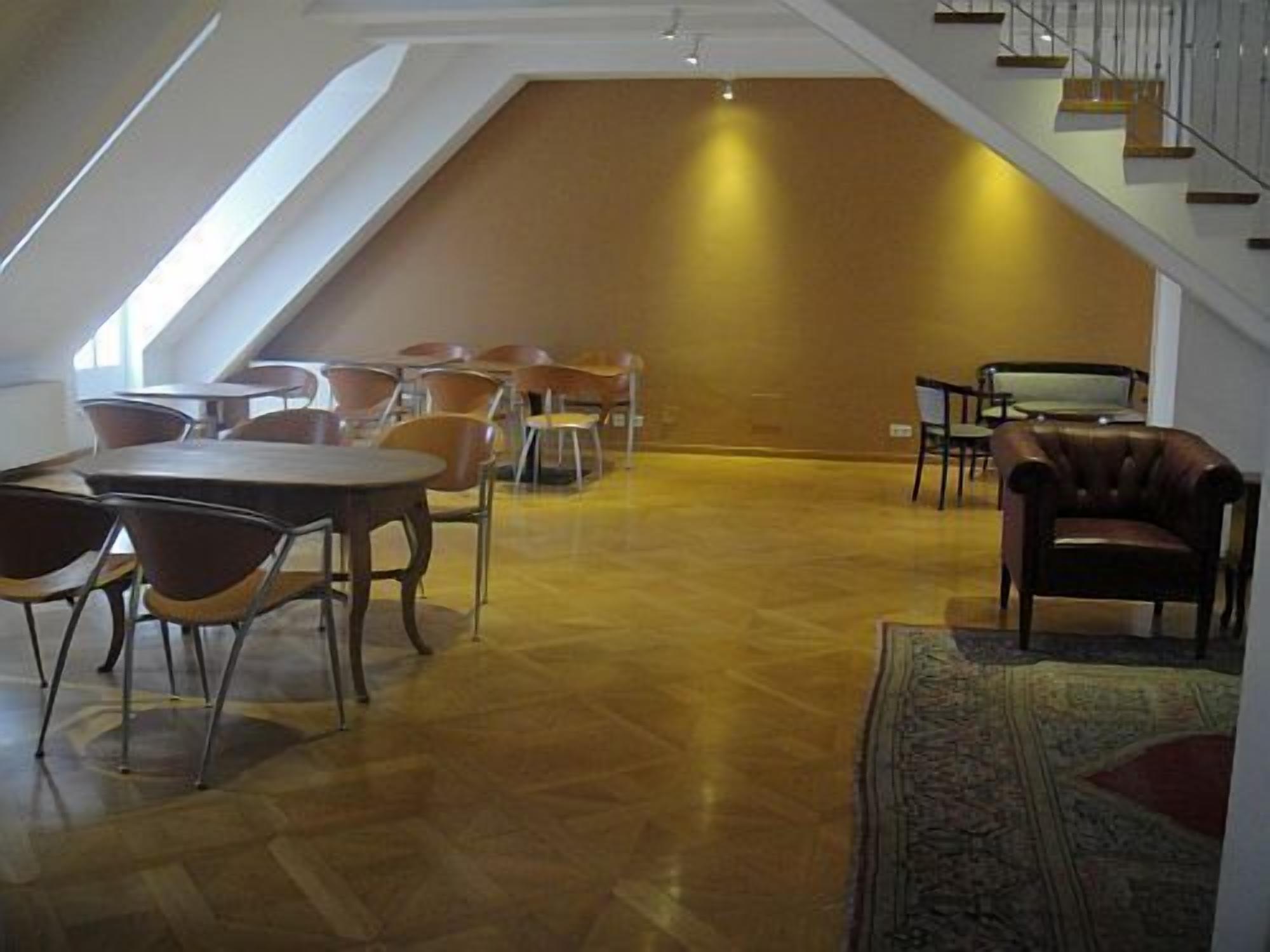 Ein geräumiger Lofts mit hohen Decken, Holzboden und einer Sitzecke mit Stühlen und Tischen.