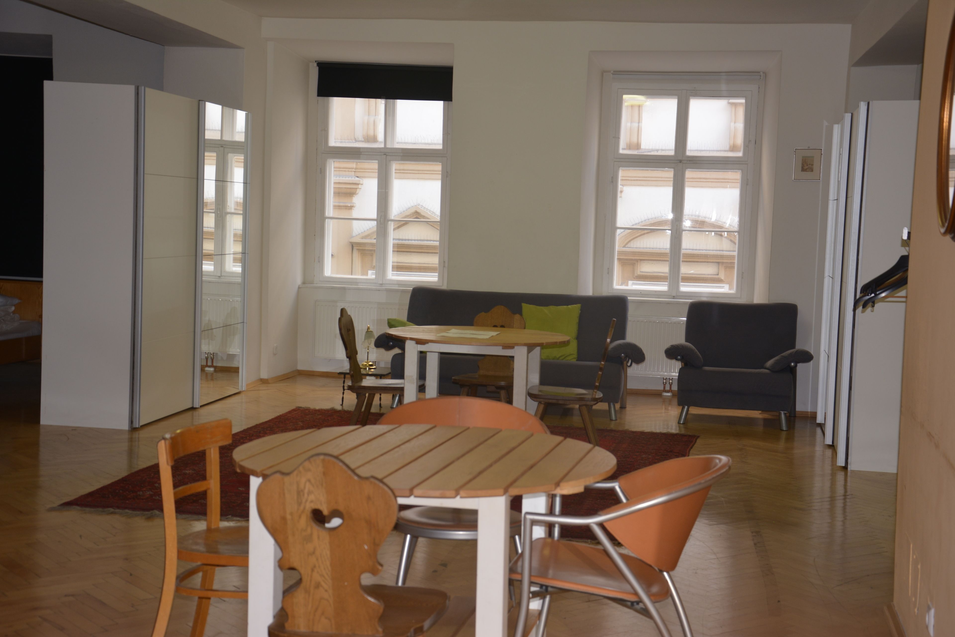 En moderne stue med spiseplads, med et træbord og stole, en sofa og et vindue med udsigt til bygninger.