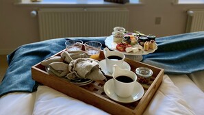 A neatly arranged breakfast tray on a bed with a view of a field through a window.