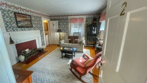 A cozy living room with a fireplace, a sofa, a rocking chair, and a dining area. - Open Hearth Inn (Trenton)
