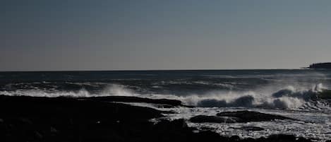 Un paysage côtier où les vagues s’écrasent sur une plage rocheuse.