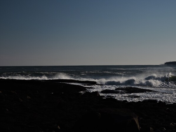 A coastal scene with waves crashing onto a rocky shore.