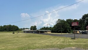 A motel with a grassy parking lot, a signboard, and a building with a green roof. - Holiday Motel Westfield (Westfield)