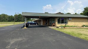 A motel with a covered parking area, a golf cart, and a vehicle parked outside. - Holiday Motel Westfield (Westfield)
