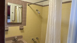 A bathroom with a sink, mirror, bathtub, and shower curtain. - Holiday Motel Westfield (Westfield)