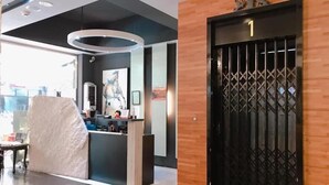Un espace d’accueil moderne avec une porte en bois portant le numéro 1, un comptoir d’accueil et une grande fenêtre donnant sur l’extérieur.