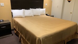 Habitación de hotel con una cama grande, una mesita de noche, un teléfono y una lámpara de pared.