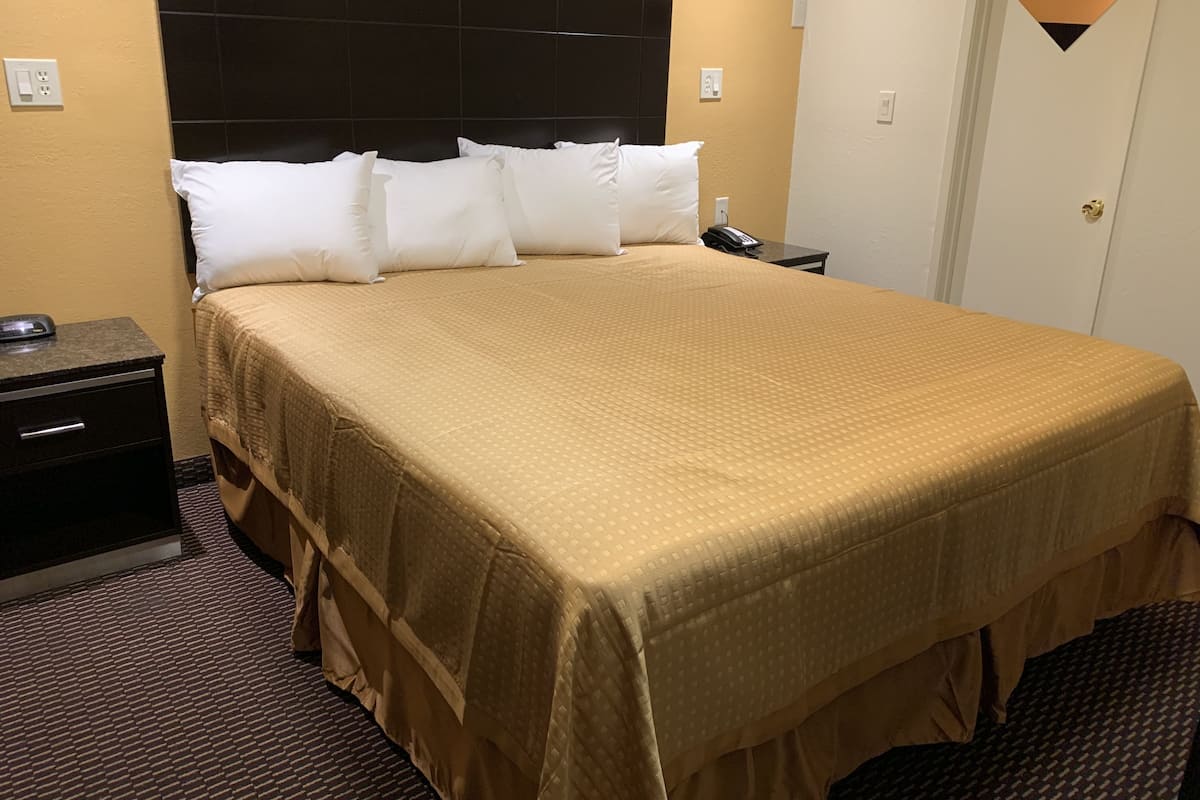 Een hotelkamer met een groot bed, een nachtkastje, een telefoon en een wandlamp.
