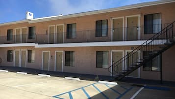 A multi-story motel with a parking lot, marked handicap parking, and a stairway to the upper level.