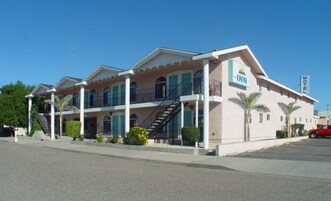 Un motel con una estructura de dos pisos, una escalera que lleva al nivel superior y un letrero que indica que es un motel INN.