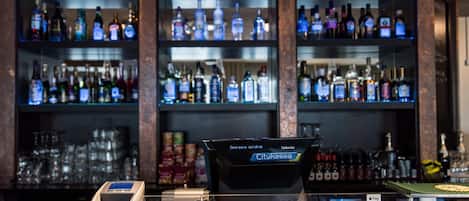 Zona de bar con una terminal de pago, una caja registradora y estantes llenos de botellas de licores.