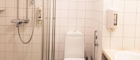 A bathroom with a toilet, a shower, and a sink.