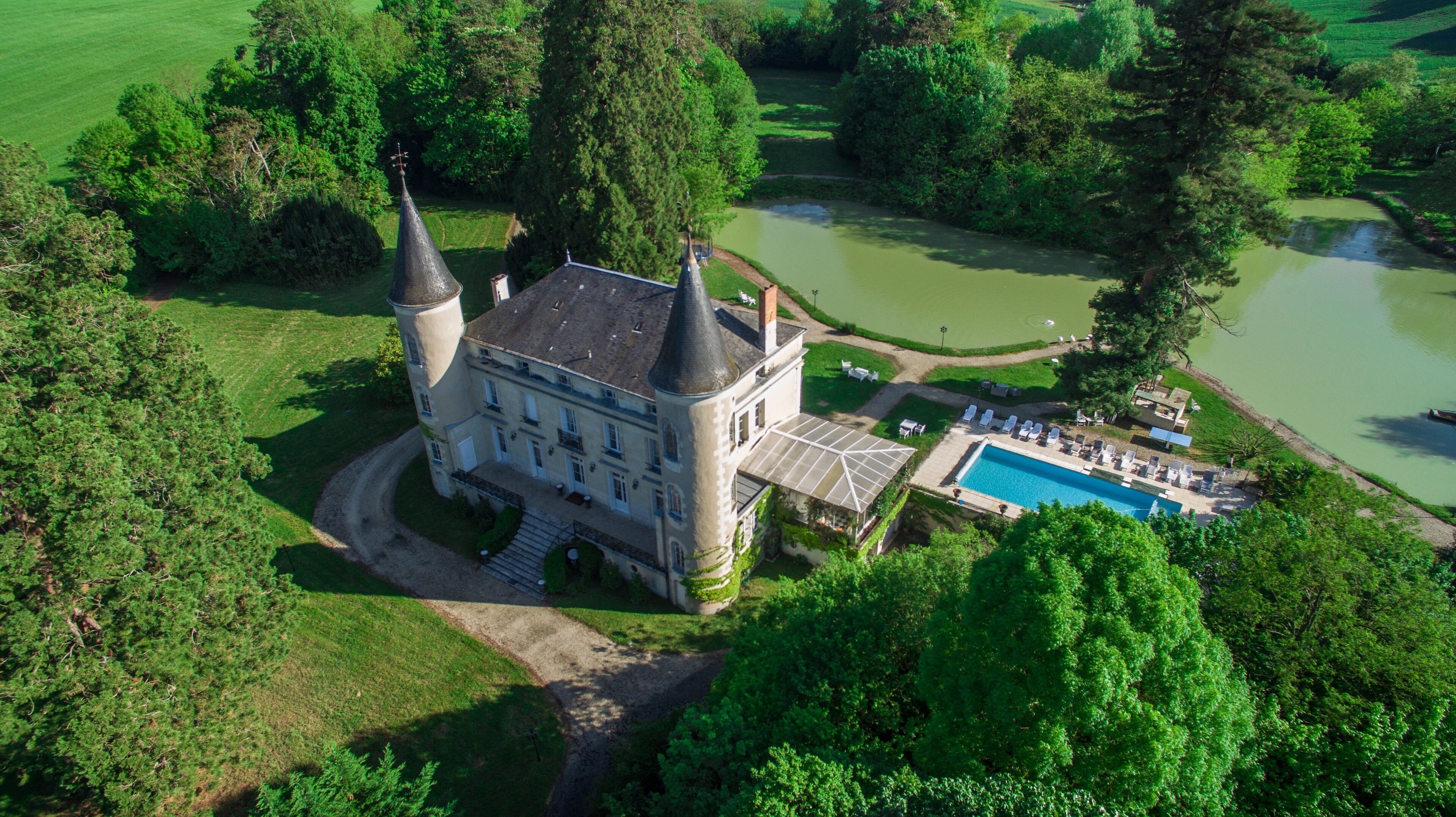 Vista aérea de um castelo com piscina e quadra de tênis.