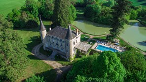 An aerial view of a castle with a swimming pool and a tennis court.
