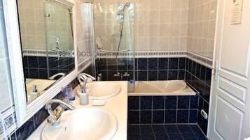 A bathroom with two sinks, a mirror, and a shower.