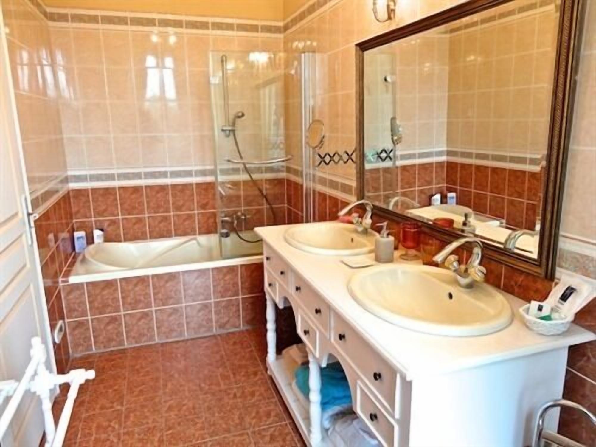 Un baño con dos lavamanos, cabina de ducha de vidrio y un espejo grande.