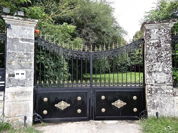 Una reja de hierro forjado negra con adornos florales y la inscripción "Chateau St. Quentin".