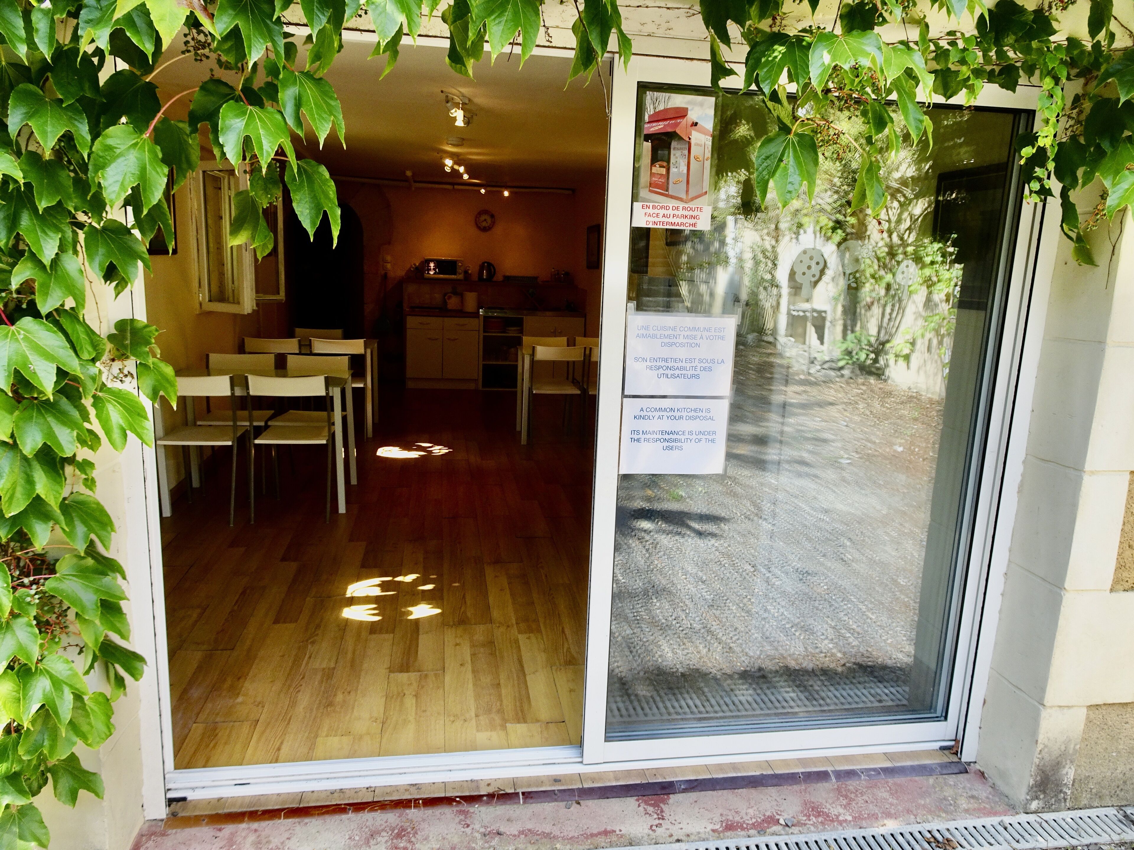 A common kitchen area with tables and chairs, a microwave, and a sign indicating it's a shared space.