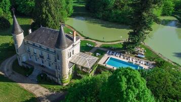 A castle with two towers, a swimming pool, and a pond.