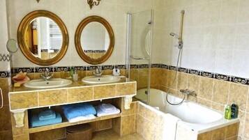 A bathroom with two sinks, a bathtub, and a shower. There are two wall-mounted mirrors and a towel rack with towels.