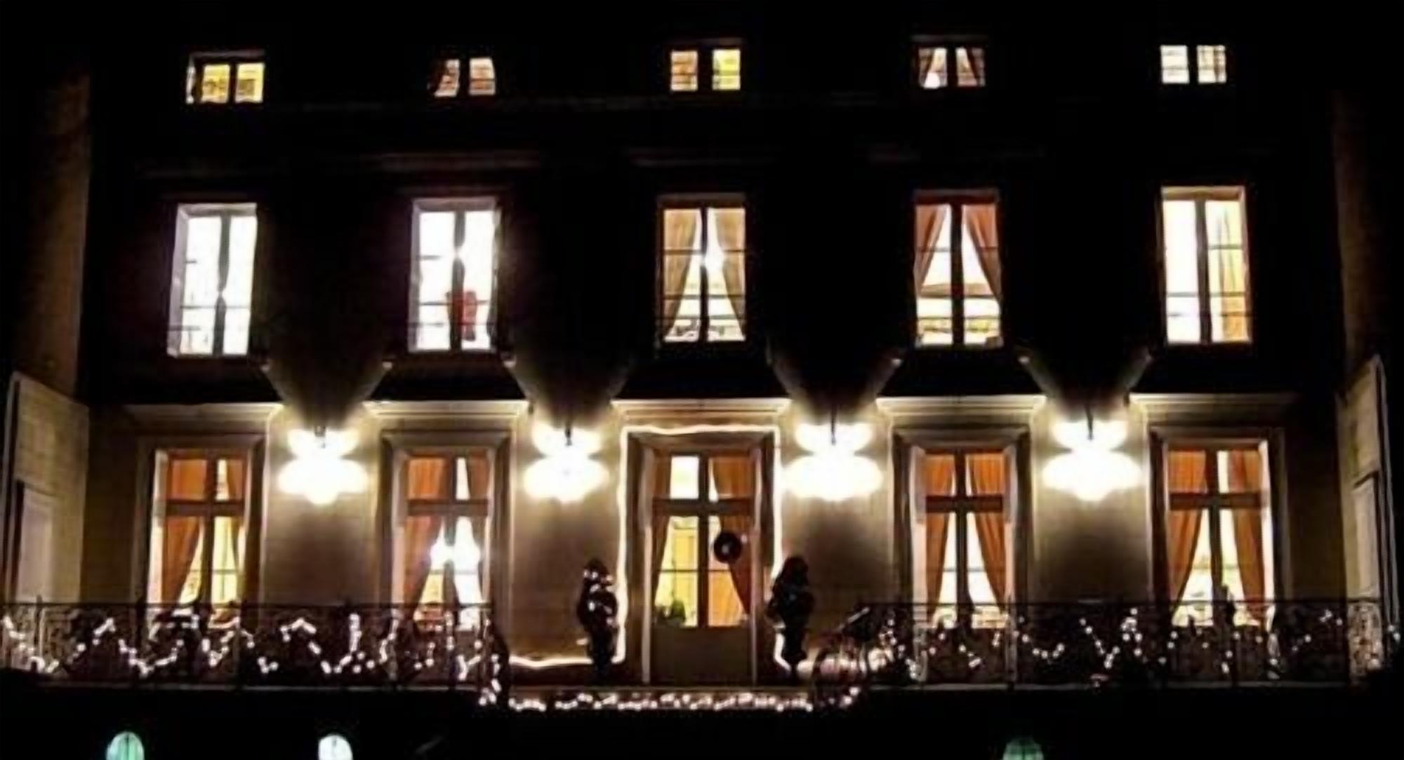 Un edificio con diverse finestre e un balcone illuminato.