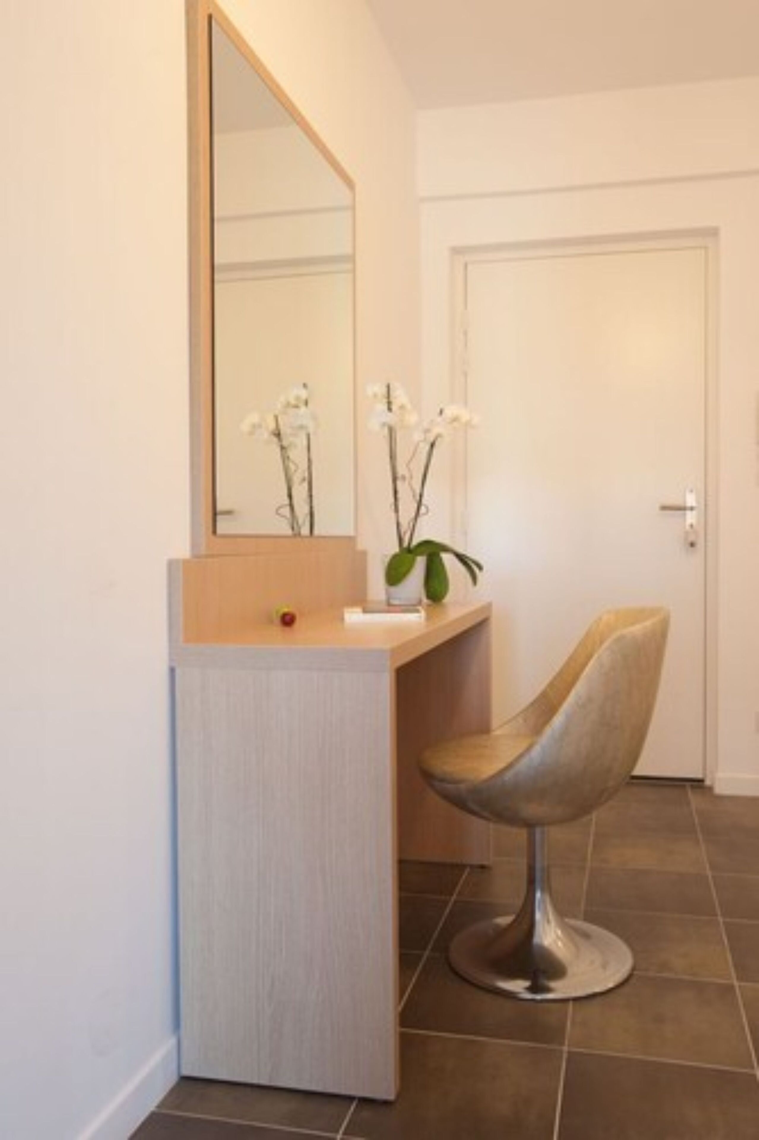 Un baño moderno con tocador, espejo y una silla.