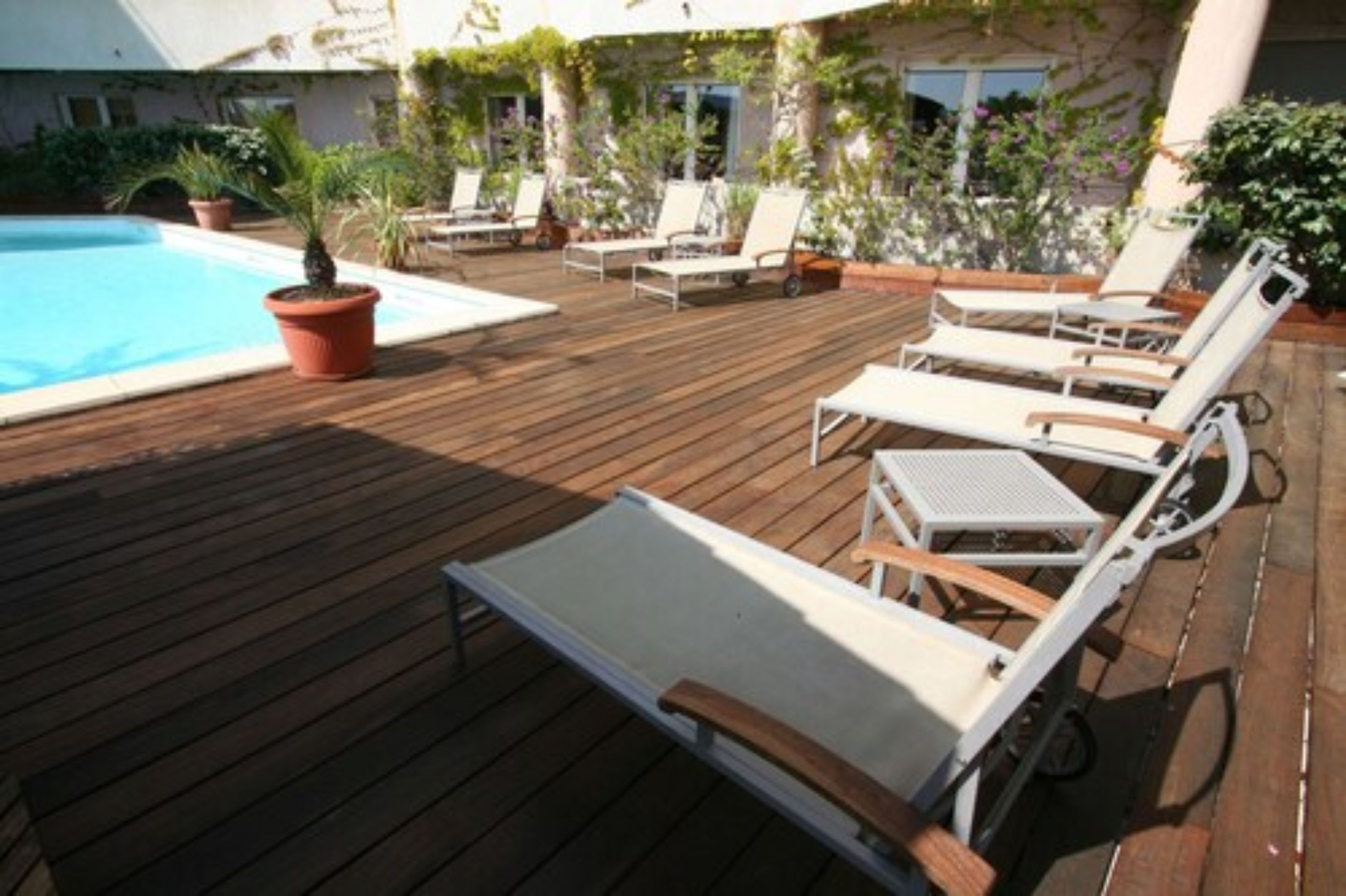 Eine Holzterrasse mit Liegestühlen und einem Pool.