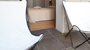A room with a bed, a chair, and a view of another room through an open door. - Résidence Hôtelière En Aparté (Porto-Vecchio)