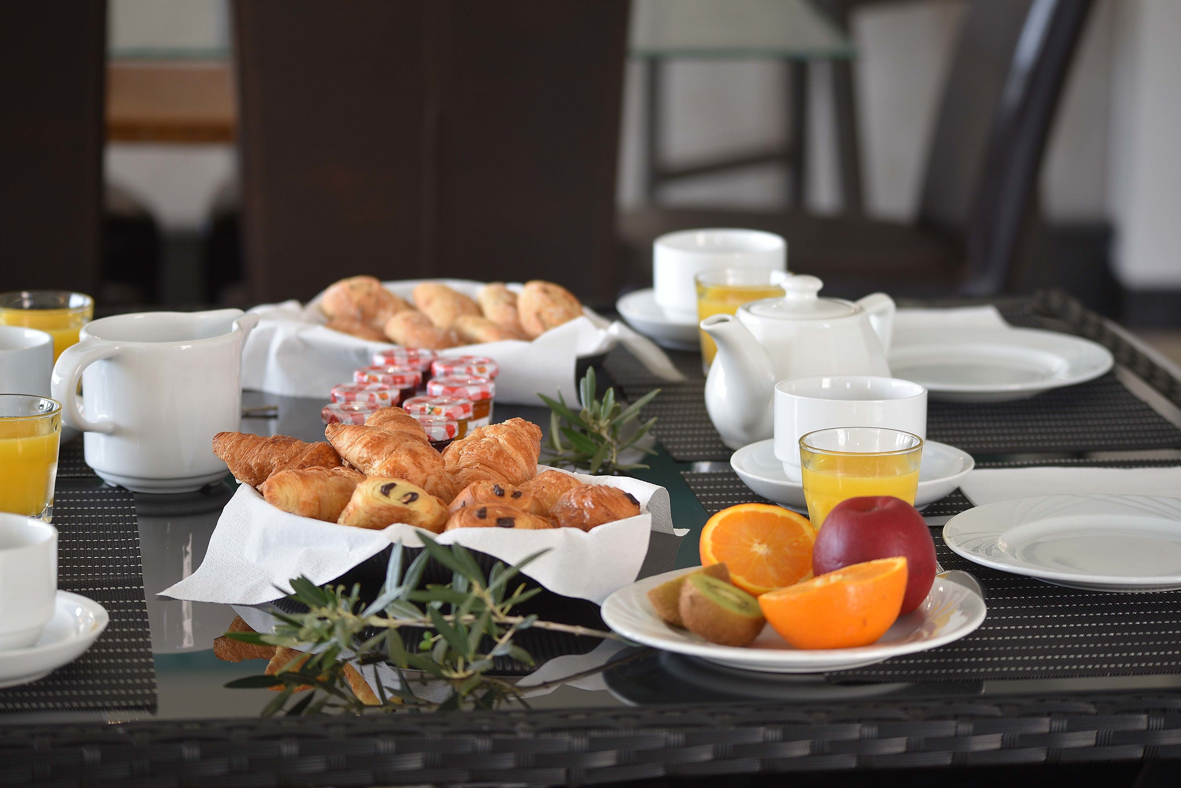 A breakfast table with croissants, pastries, fruit, and coffee.