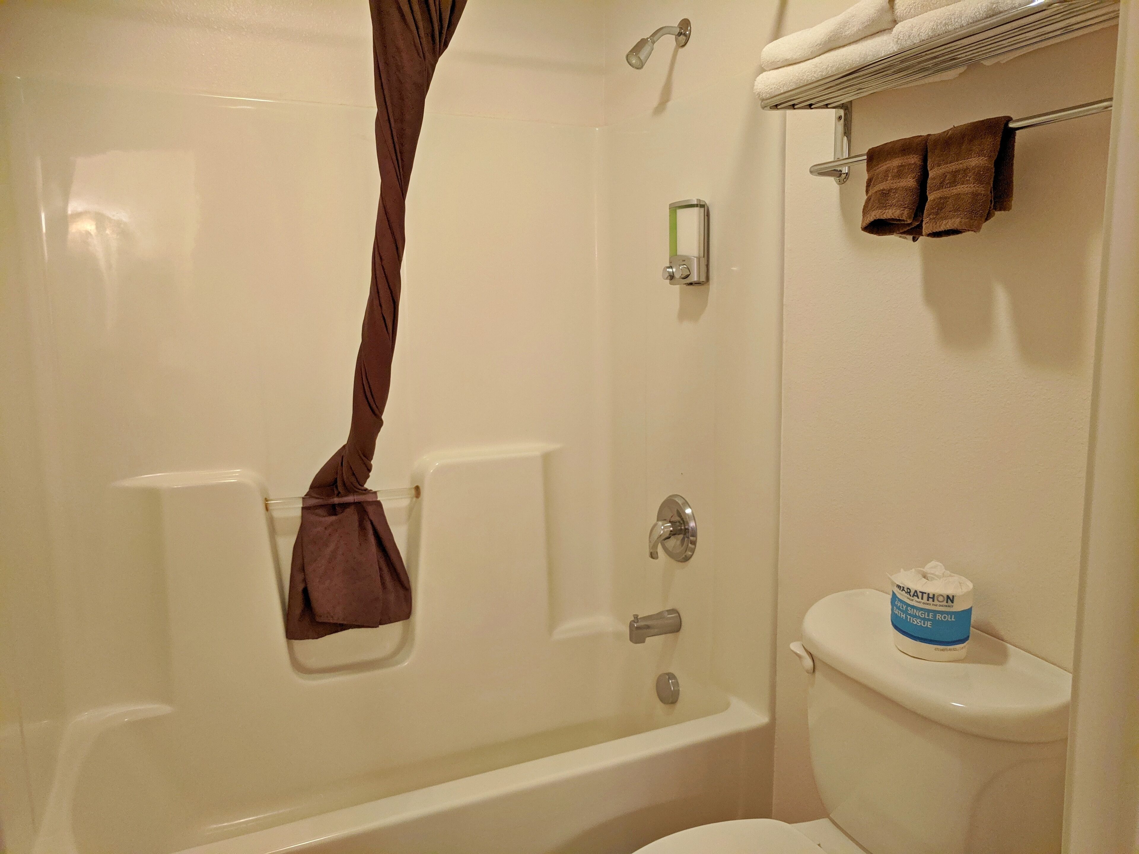 A bathroom with a bathtub, toilet, and a towel rack.