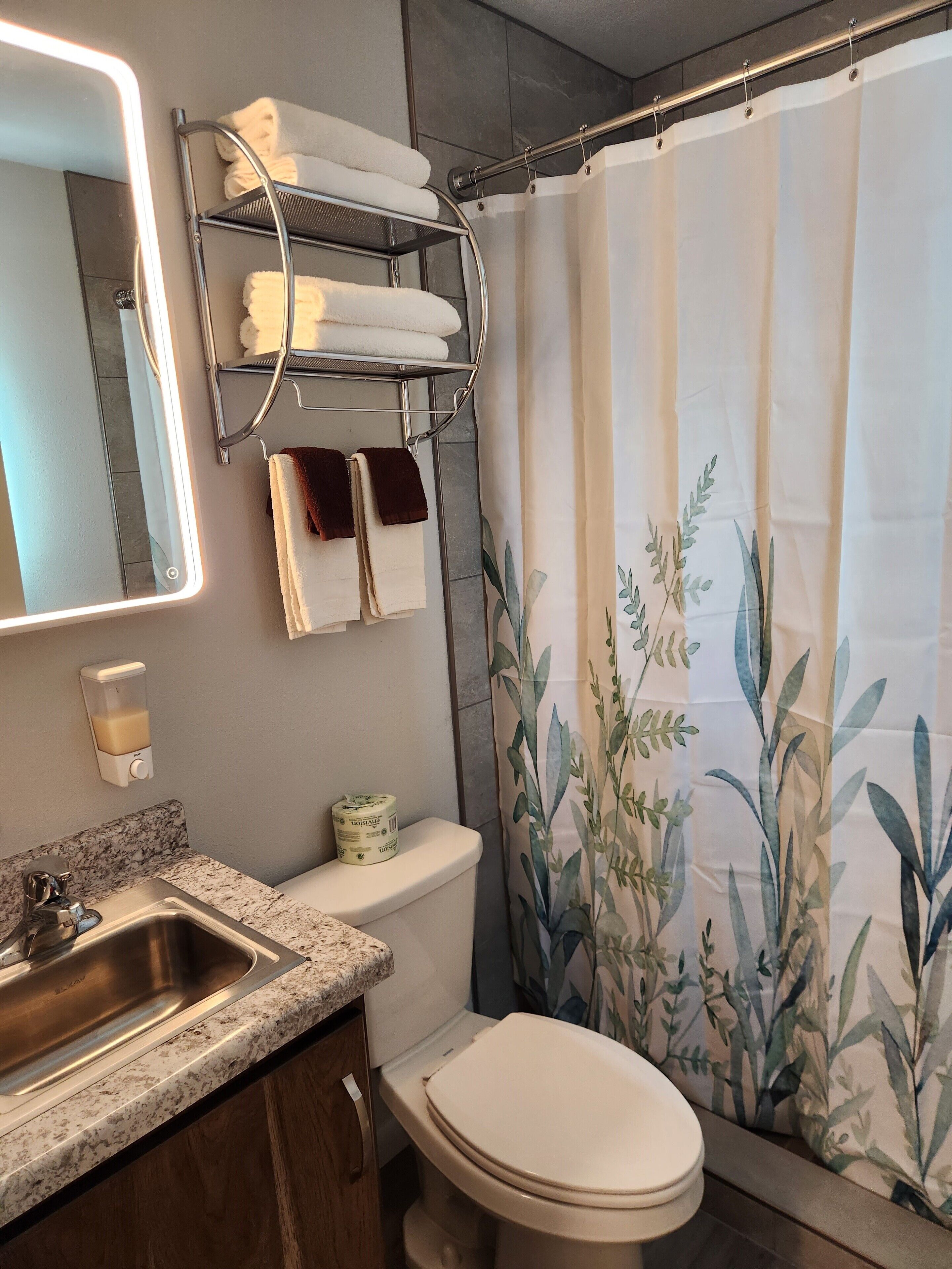 A bathroom with a sink, toilet, and a towel rack with multiple towels.