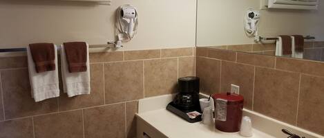 A bathroom with a sink, mirror, towel rack, and a coffee maker.