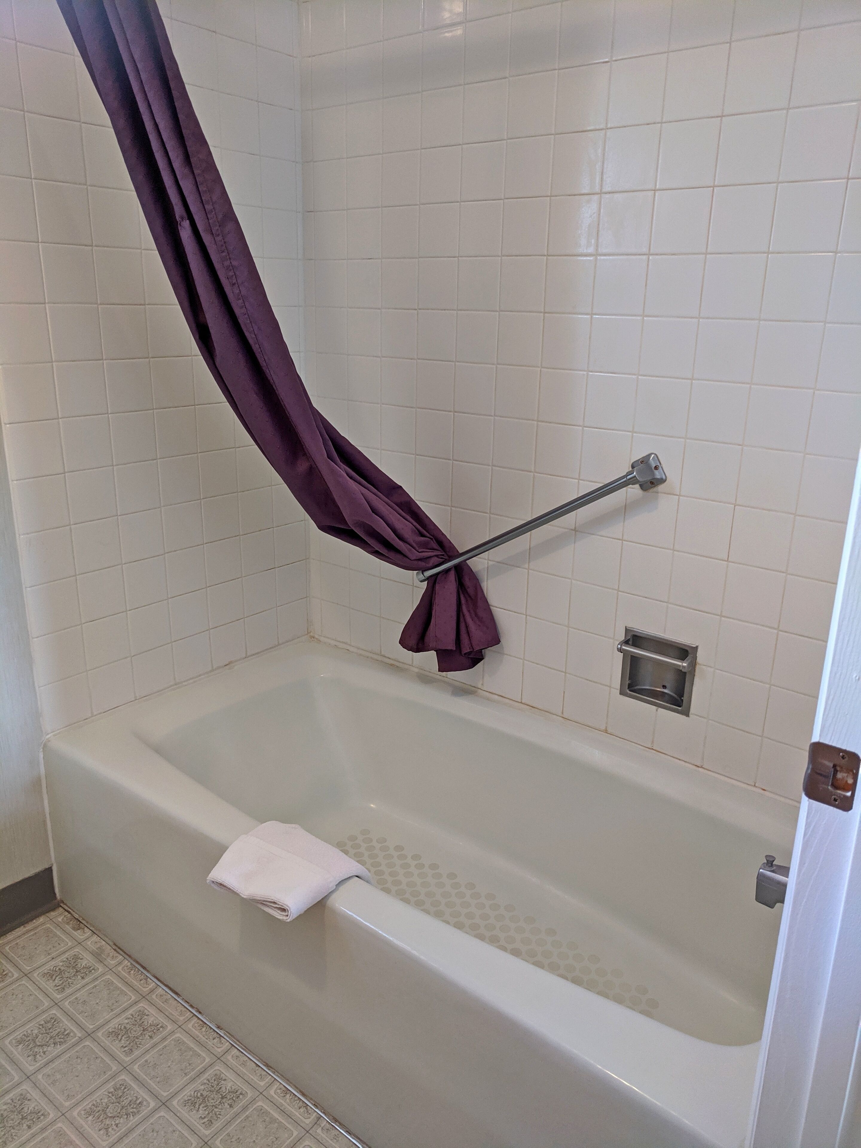 A bathroom with a bathtub, a shower curtain, and a towel rack.