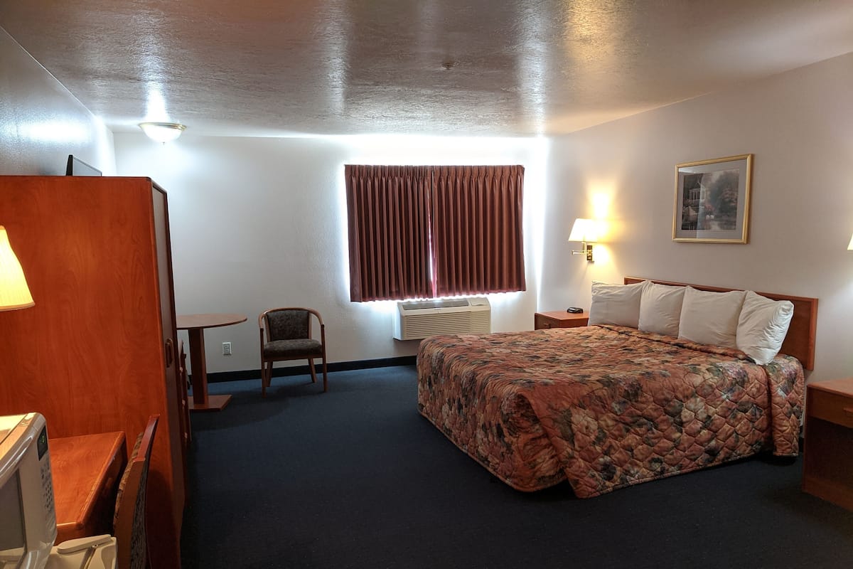 Ein Hotelzimmer mit einem Bett, einem Sessel, einem Schreibtisch und einer Lampe.