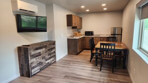 Una cocina moderna con armarios de madera, microondas integrado y un comedor con mesa y sillas de madera.
