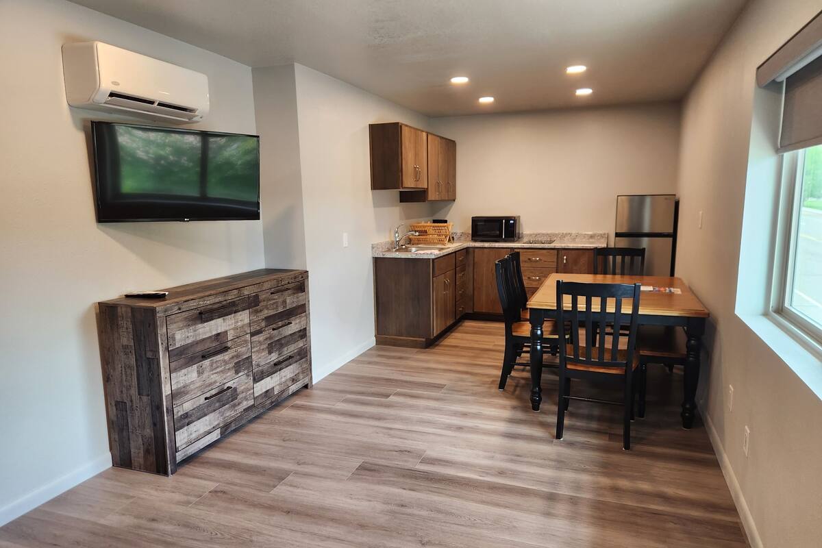Eine moderne Küche mit Holzausbau, einer eingebauten Mikrowelle und einem Essbereich mit Holztisch und -stühlen.
