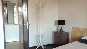 A bedroom with a bed, a bedside table with a lamp, a floor lamp, a wardrobe, and a door leading to a bathroom. - The Resid For Calixte (Perouges)