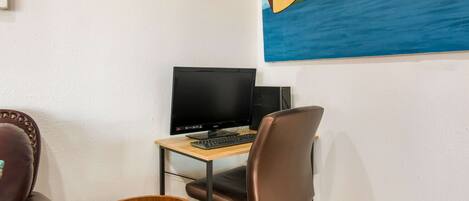 Una habitación con un escritorio, una computadora, una silla y una batería.