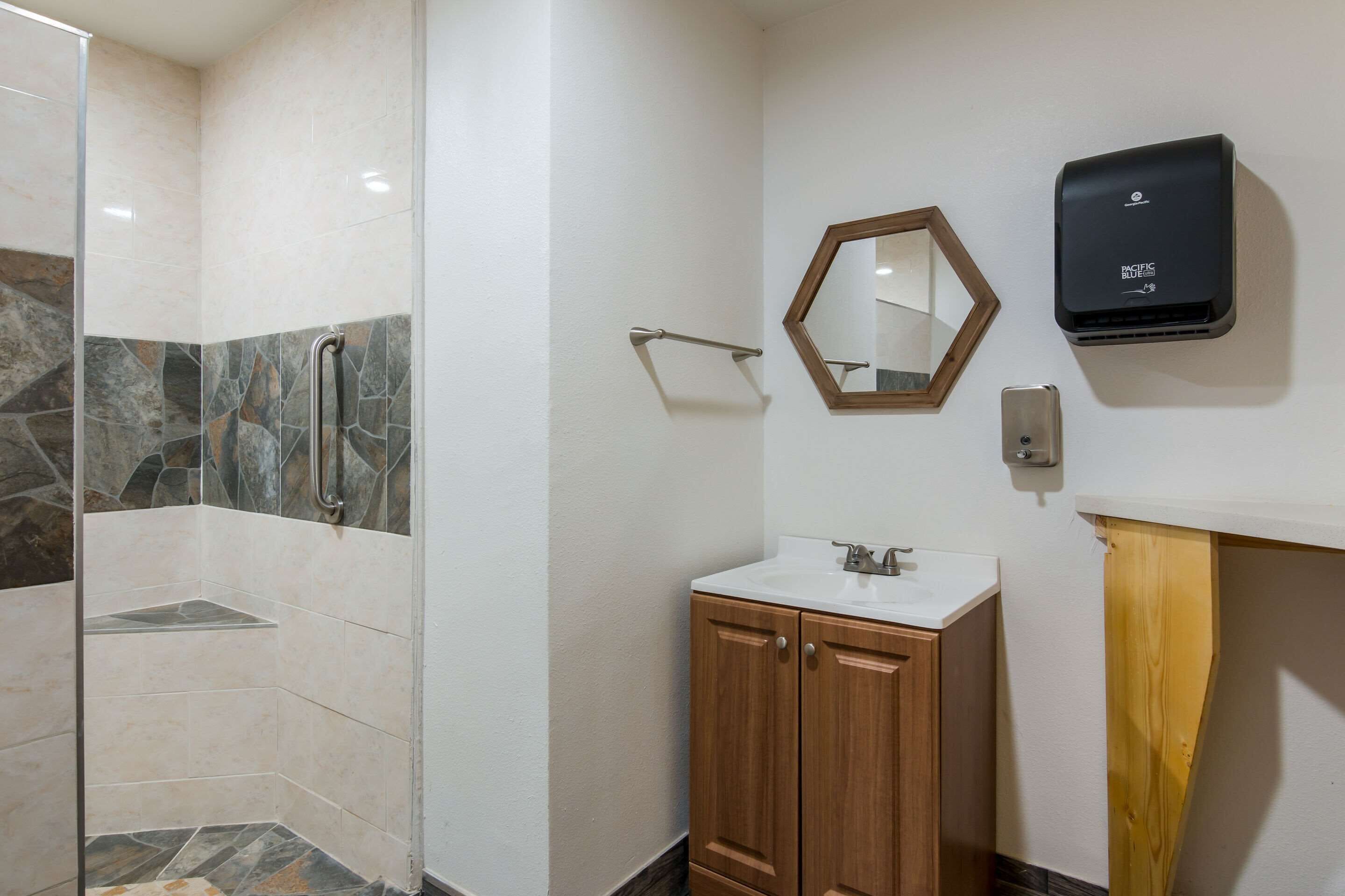 Une salle de bain avec une douche, un lavabo et un miroir.